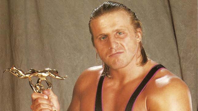 Owen Hart with his beloved Slammy Award statue in a 1996 WWE promotional image.