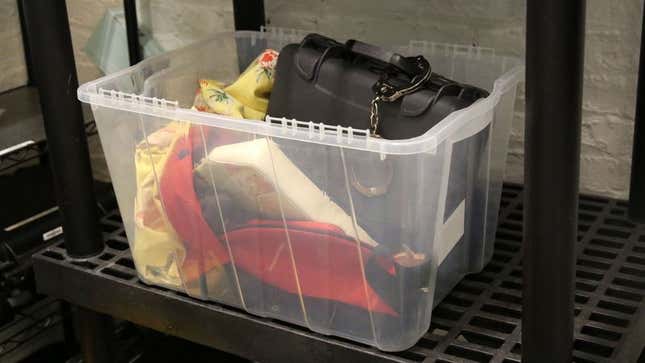 A black briefcase, along with various forgotten items, sits in a plastic bin.