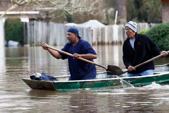 Jackson, Mississippi homeowners use shovels to work their way through Pearl River floodwater.