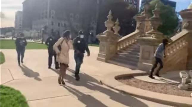 Armed escorts walk Michigan State Rep. Sarah Anthony into the state capitol building.