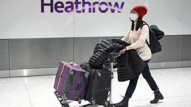 Passengers wear face masks as the push their luggage after arriving from a flight at Terminal 5 of London Heathrow Airport in west London on January 28, 2020. 
