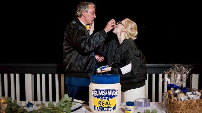 Newlywed couple in front of a "Helms & Mayo" mayonnaise jar wedding cake
