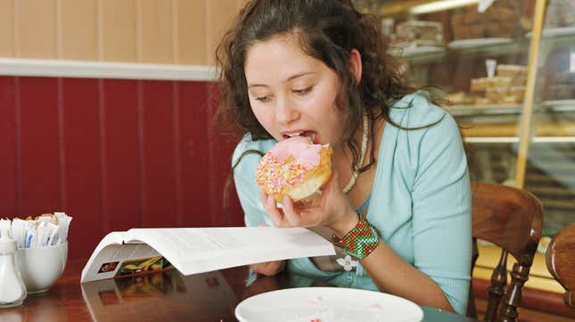 Girl reading and eating a doughnut