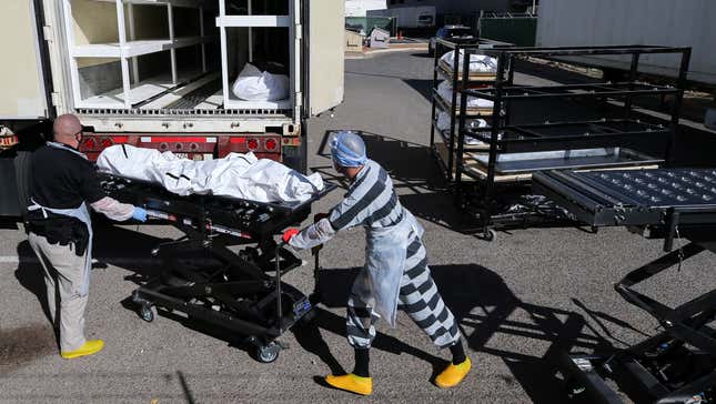 An inmate (center) works loading bodies wrapped in plastic into a refrigerated temporary morgue trailer in a parking lot of the El Paso County Medical Examiner’s office on Nov. 17, 2020 in El Paso, Texas.