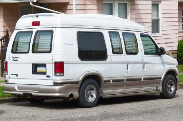 Una furgoneta de conversión ford Econoline estacionada fuera de una casa