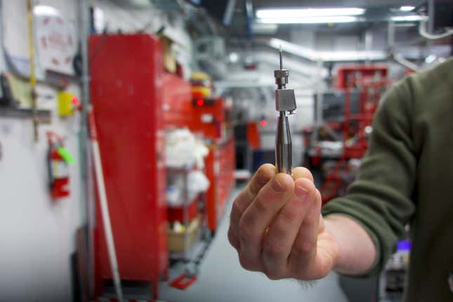 A researcher holds up the needle that injected their sample into a laser beam.