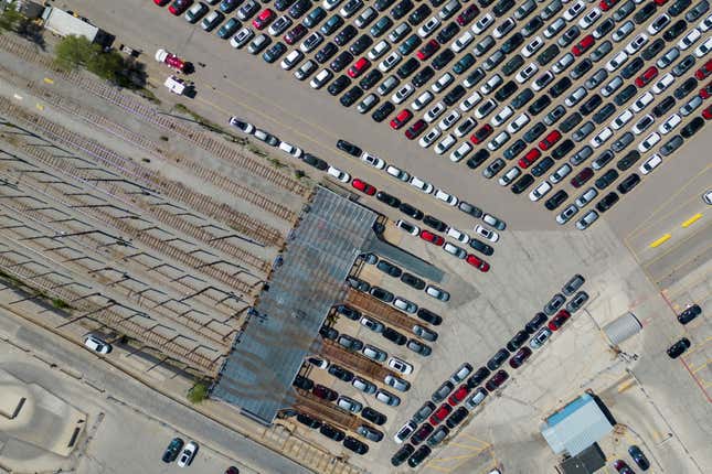 A birds-eye view of a Ford assembly plant, showing lines of cars in different colors outside on tarmac.