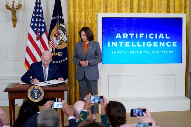 FILE - President Joe Biden signs an executive on artificial intelligence in the East Room of the White House, Oct. 30, 2023, in Washington. Vice President Kamala Harris looks on at right. The White House said Wednesday, Feb. 21, 2024, that it is seeking public comment on the risks and benefits of having an AI system&#39;s key components publicly available for anyone to use and modify. (AP Photo/Evan Vucci, File)