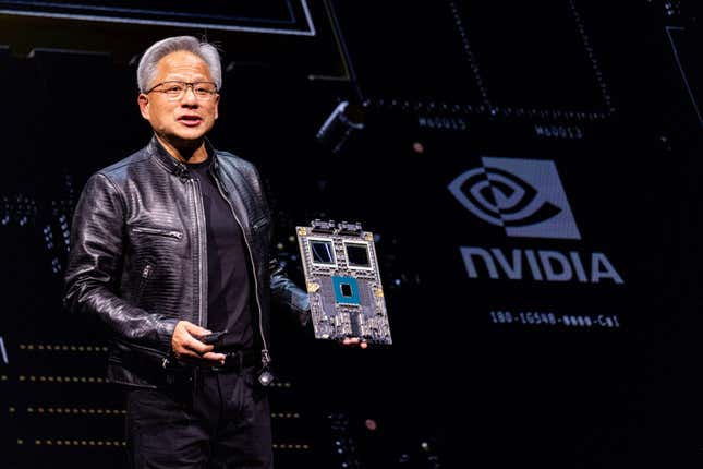 Jensen Huang holding a chip platform in front of a black backdrop with the Nvidia logo