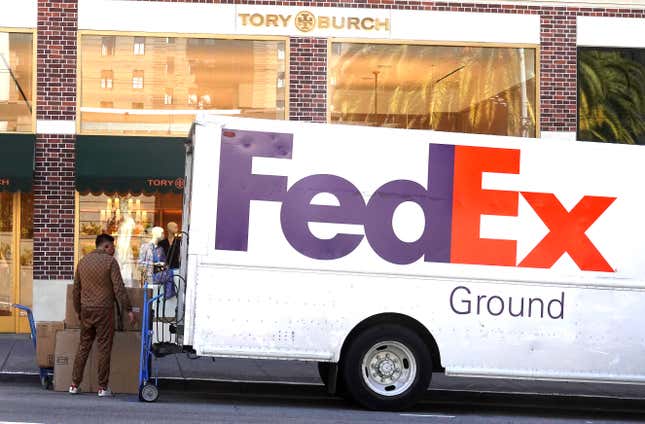 A worker loads packages into a FedEx truck. 