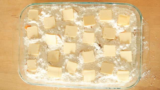 Butter slices on top of cake mix in a casserole dish.