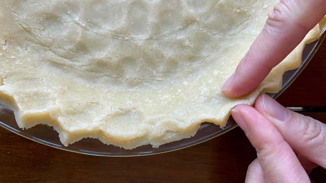 Fingers crimping a pie shell.