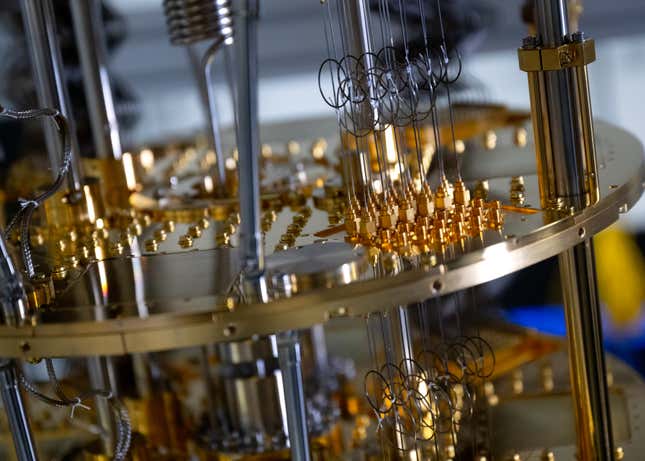 close up of gold wires, screws, and buttons on a plate of a quantum computer