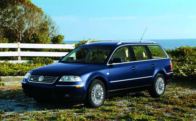 A dark blue VW Passat wagon with the W8 engine parked on a bluff in front of the ocean.