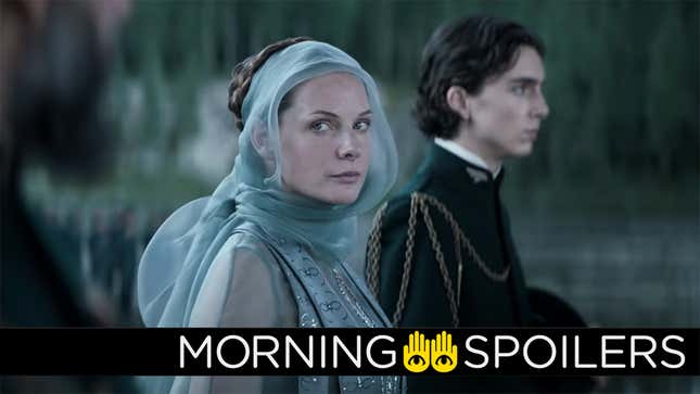 Dune's Rebecca Ferguson (Lady Jessica) wears a dressy blue gown with a see-through blue veil wrapped around her head while standing next to Timothée Chalamet's Paul Atreides in black military dress gear.