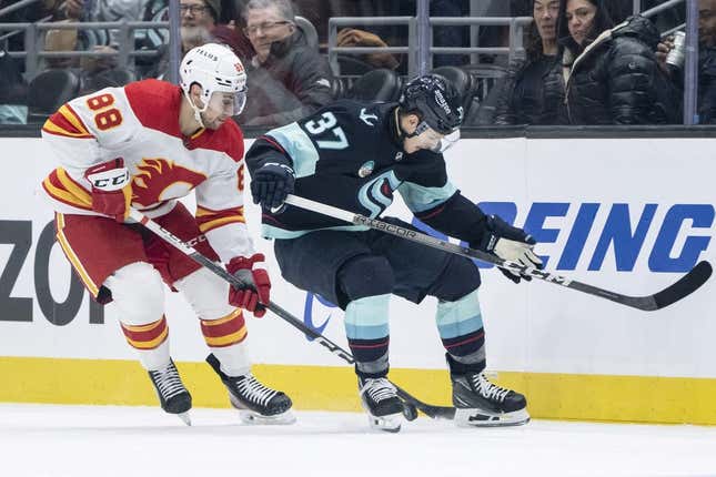 Nov 20, 2023; Seattle, Washington, USA; Seattle Kraken forward Yanni Gourde (37) and Calgary Flames forward Andrew Mangiapane (88) battle for the puck during the first period at Climate Pledge Arena.