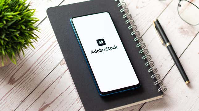 A phone bearing the Adobe Stock logo on top of a notebook.