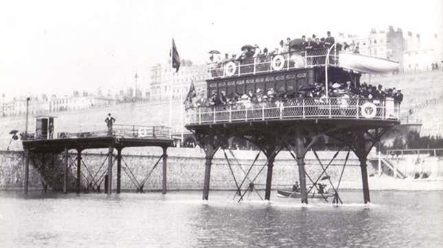 A black and white photo of an elevated train running through the sea. 