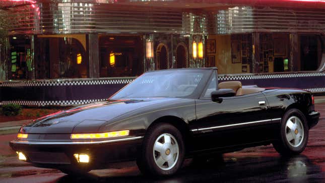 A photo of a black Buick sports car parked in front of a diner. 