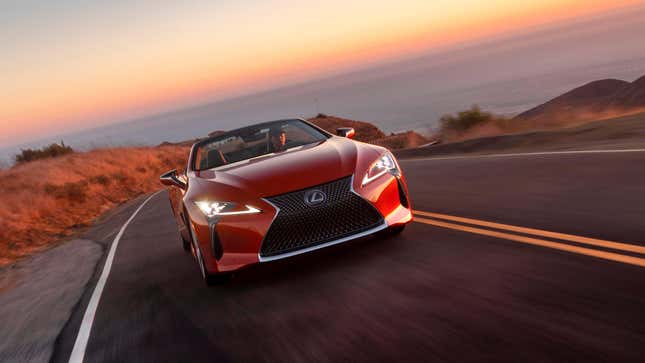 A red LC500 convertible driving away from the ocean 