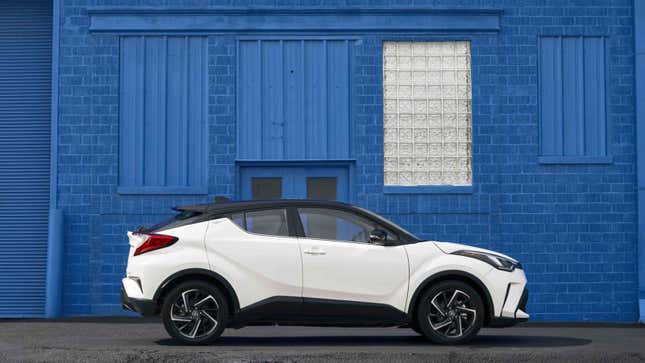 A photo of a white Toyota C-HR SUV parked next to a blue building. 