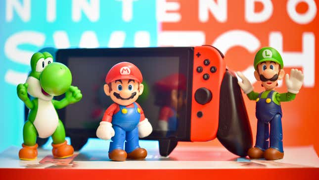 Mario figurines stand around a Nintendo Switch.