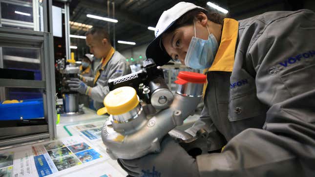 A photo of a worker assembling a turbocharger in a factory. 