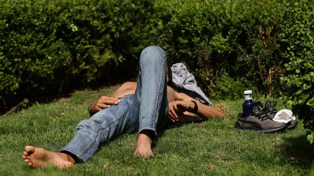 A man lies on the grass amid intense temperatures in Madrid on May 19, 2022.