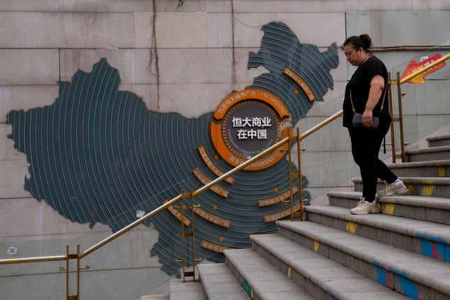 FILE - A woman walks by a map showing Evergrande development projects in China, as she heads to an Evergrande city plaza in Beijing on Sept. 18, 2023. China’s central bank announced new rules late Wednesday, Jan. 24, 2024, meant to expand access to commercial bank loans for property developers, part of a raft of policies aimed at spurring the slowing economy and stabilizing financial markets. (AP Photo/Andy Wong, File)