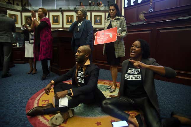 Rep. Tray McCurdy, D-Orlando and Rep. Angie Nixon, D-Jacksonville sit on the Florida Seal in protest as debate stops on Senate Bill 2-C: Establishing the Congressional Districts of the State in the House of Representatives Thursday, April 21, 2022 at the Capitol in Tallahassee, Fla. The session was halted on the protest.