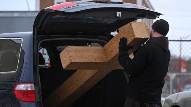 Ein Foto einer Person, die ein Kreuz in den Kofferraum ihres Autos lädt. 