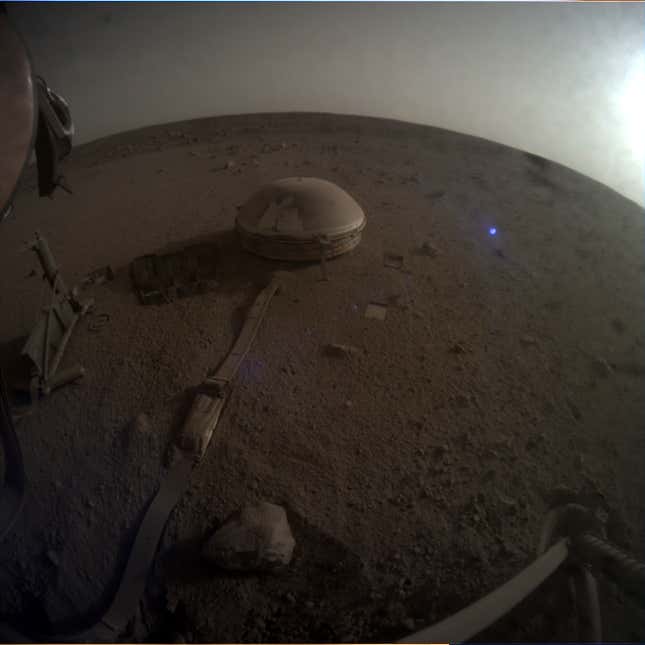 Dark view of InSight's seismometer sitting on the Martian surface.