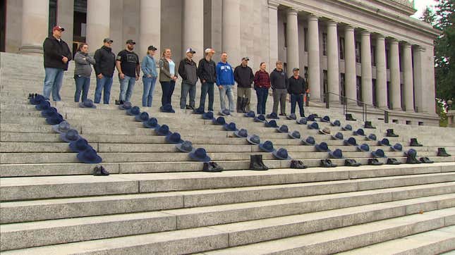 Anti-vax former Washington State Patrol troopers and other employees lay hats of their fired colleagues on the state Capitol in a protest against the state's employee vaccination requirement.