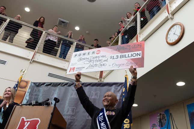 Cheng &quot;Charlie&quot; Saephan holds display check above his head after speaking during a news conference where it was revealed that he was one of the winners of the $1.3 billion Powerball jackpot at the Oregon Lottery headquarters on Monday, April 29, 2024, in Salem, Ore. (AP Photo/Jenny Kane)