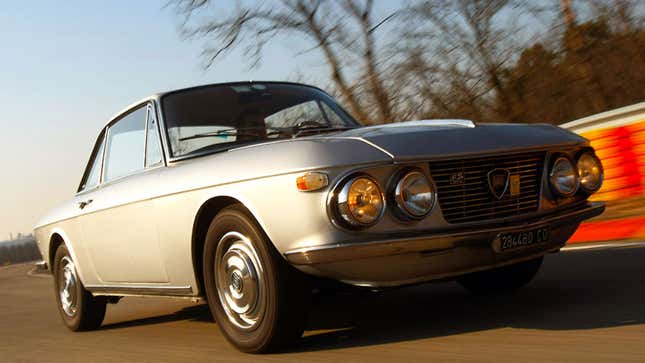 A photo of a silver Lancia Fulvia sports car being driven on a track. 