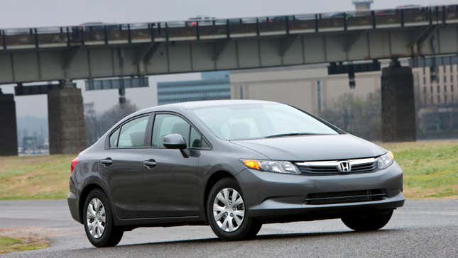 A gray Honda Civic looking incredibly dull parked in front of an ugly bridge