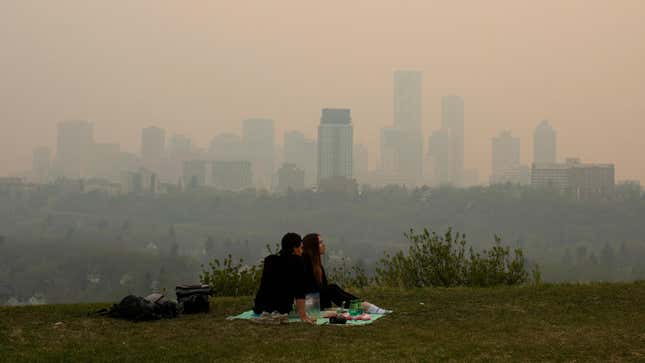 Smoke from wildfires blankets the city as a couple has a picnic in Edmonton, Alberta on May 11, 2024.