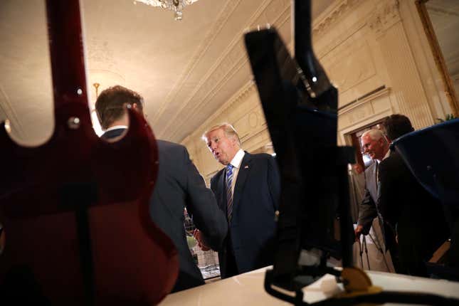 Trump shakes hands with business owners in front of a display of Marucci guitars.