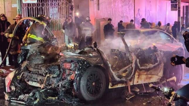 A photo of firefighters around the remains of a Waymo car that burned down. 