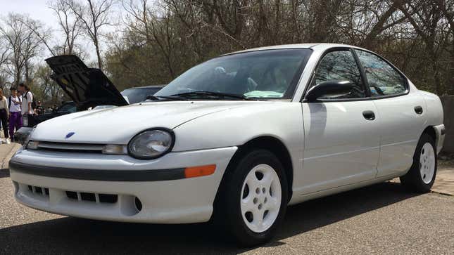 a white first-gen doge neon parked in front of trees