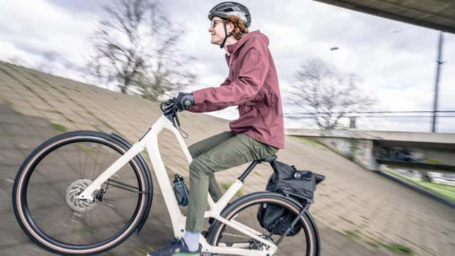 A photo of a happy person riding a bike up a concrete hill. 