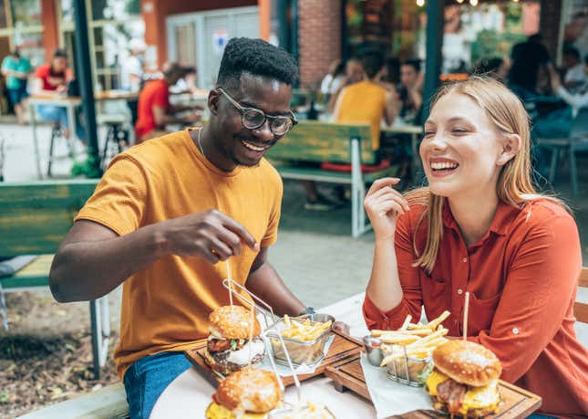 Des amis mangent des hamburgers et des frites dans un restaurant en plein air.