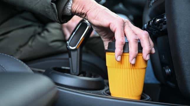 A woman putting a cup in the cupholder of a mini
