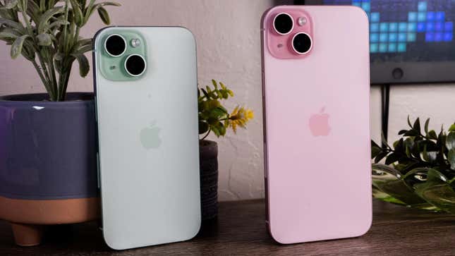 Two iPhone 15s standing in a row, one in green and the other pink.
