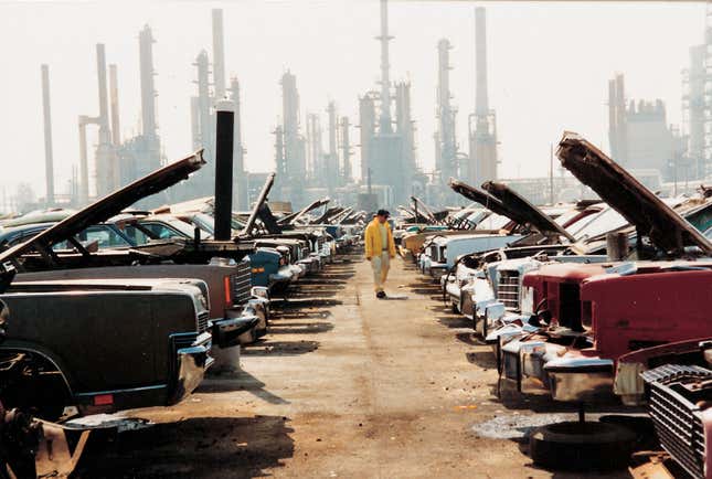 A photo showing a person walking among wrecks of cars. 