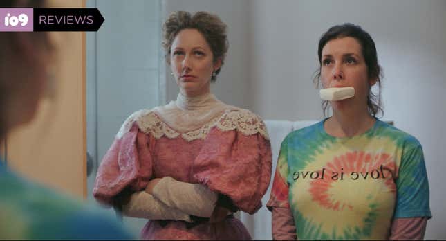 A woman (Judy Greer) in a frilly, old-fashioned gown looks irritated next to a woman (Melanie Lynskey) wearing a tie-dye shirt with a bar of soap in her mouth in Lady of the Manor.
