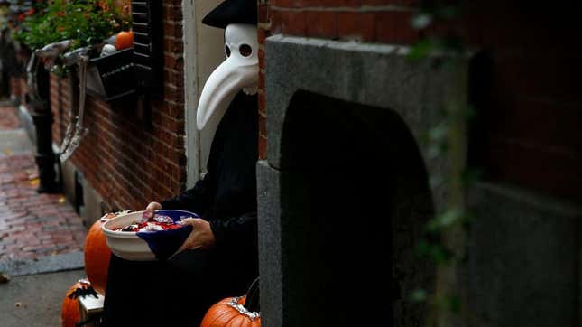 Person in plague doctor costume hands out candy on street