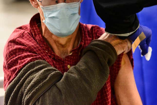 A man exposes his arm to get a Flu shot as a doctor wipes the space where he will get the shot with alcohol.
