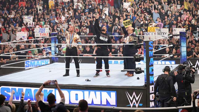 This undated photo provided by the WWE shows from left, Dwayne &quot;The Rock&quot; Johnson, Roman Reigns and Paul Heyman in the ring during WWE Smackdown. As WWE gears up for its biggest annual premium live event in April 2024, the company continues to harness the power of its social media presence to reach its fans. A key component of that strategy is YouTube, where WWE has hit an important milestone: reaching 100 million subscribers. (Scott Brinegar/WWE via AP)