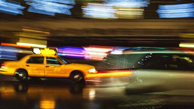 Vemos algunos autos, especialmente un taxi amarillo cruzando la Quinta Avenida durante la Navidad, vemos algunas estrellas de la luz navideña en Nueva York rayadas encima de Taxi.